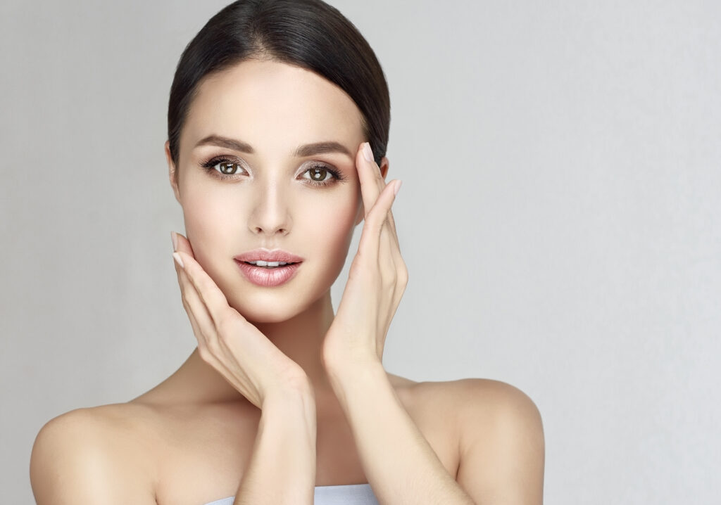 A woman framing her face with her hands and showing the results of a facelift procedure