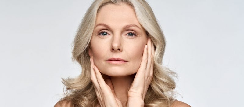 Middle age woman with smooth skin shows her rejuvenated face following facelift